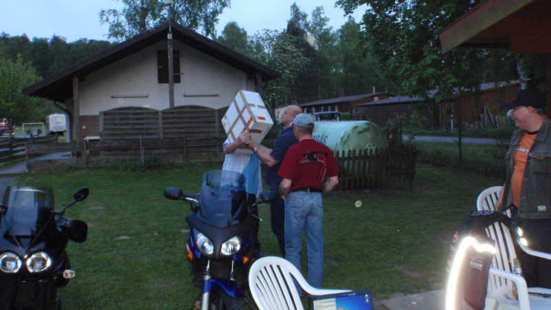 Mehrere Personen im Garten mit Motorrädern und Kartons