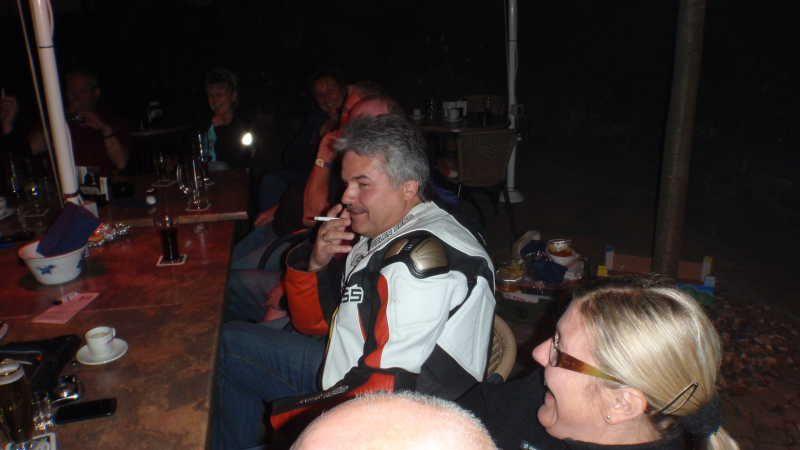 Mehrere Personen sitzen zusammen an einem Tisch, eine Person raucht eine Zigarette.