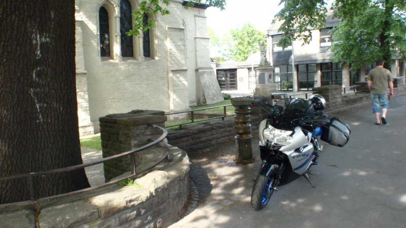 Motorrad parkte neben einem alten Gebäude mit Steinmauer an einem sonnigen Tag