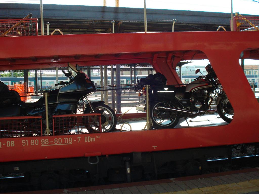 Zwei Motorräder in einem roten Autotransportwagen auf einem Bahnhofsgleis