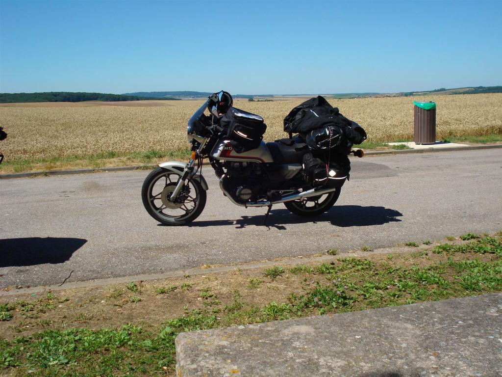Motorrad mit Gepäck auf einer Straße neben Feldlandschaft