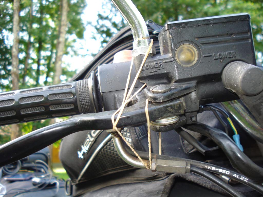 Nahaufnahme des rechten Lenkgriffs und der Bremsflüssigkeitsanzeige eines Motorrads mit Gummiband