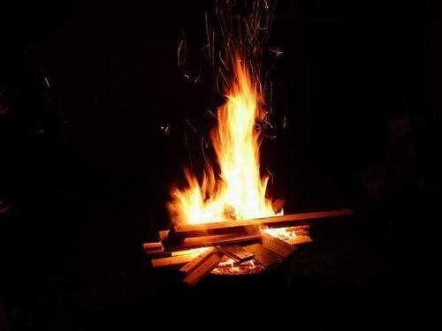 Lagerfeuer mit brennenden Holzscheiten vor dunklem Hintergrund