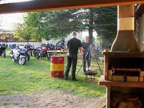 Zwei Personen beim Grillen im Freien neben Motorrädern auf einer Wiese
