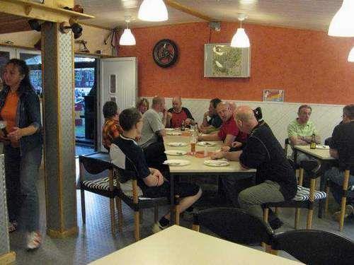 Menschen sitzen an einem langen Tisch in einem Restaurant oder einer Kantine