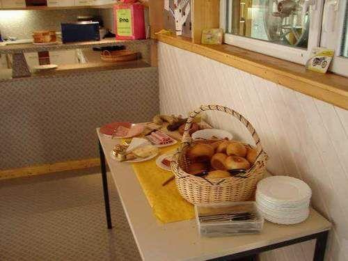 Korb mit Brötchen und Teller auf einem Tisch in einem einfachen Raum