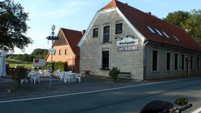 Gebäude mit dem Schild Café Bleifrei und Außenbereich mit Tischen und Stühlen neben einer Straße