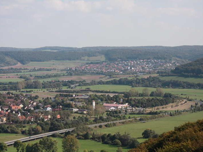 Landschaft mit Dörfern, grünen Feldern und bewaldeten Hügeln im Hintergrund