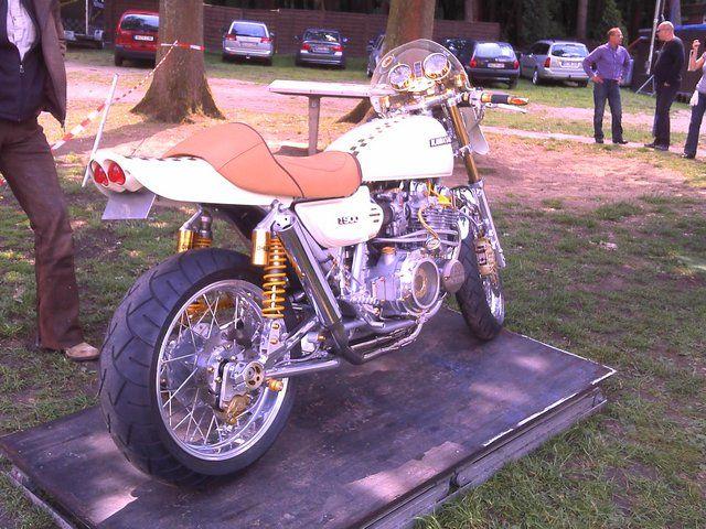 Weißes klassisches Motorrad mit braunem Sitz auf einer Plattform im Freien