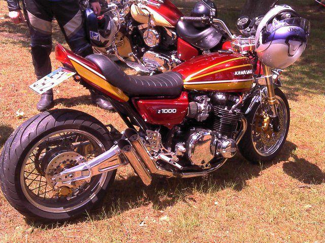 Rotes Kawasaki Z1000 Motorrad stehend auf Gras mit Helm auf Lenker