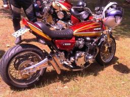 Rotes Kawasaki Z1000 Motorrad stehend auf Gras mit Helm auf Lenker