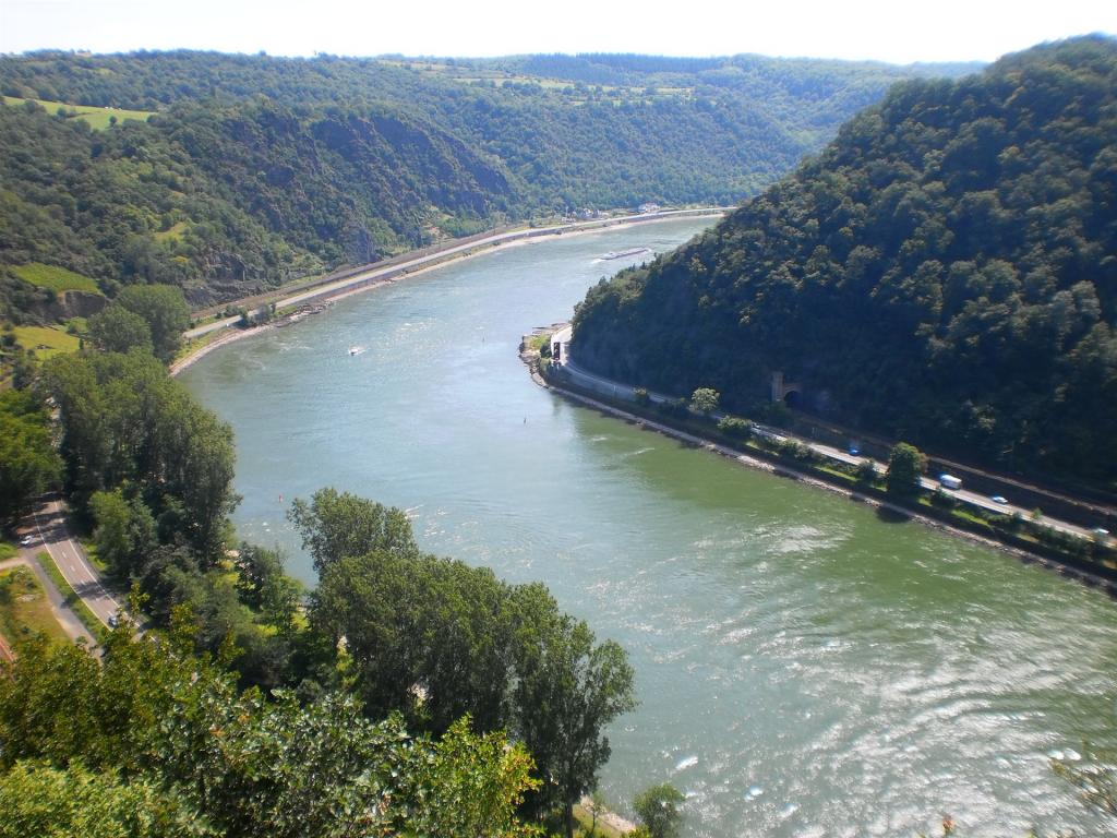 Fluss schlängelt sich zwischen bewaldeten Hügeln mit Straßen an den Ufern