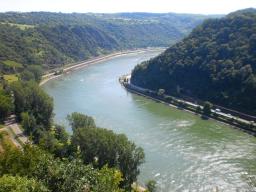 Fluss schlängelt sich zwischen bewaldeten Hügeln mit Straßen an den Ufern