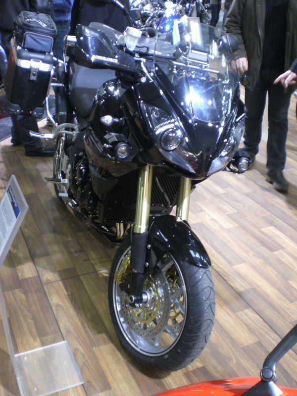 Schwarzes Motorrad mit Rennverkleidung auf einer Holzmessefläche stehend