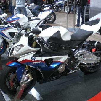 Sportliches BMW Motorrad in Weiß, Blau und Rot auf einer Messe mit weiteren Motorrädern im Hintergrund