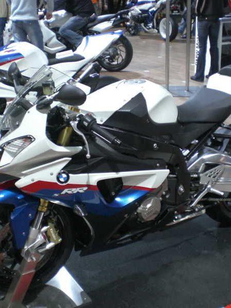 Sportliches BMW Motorrad in Weiß, Blau und Rot auf einer Messe mit weiteren Motorrädern im Hintergrund