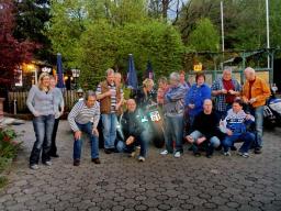 Gruppe von Menschen in lockerer Haltung im Freien vor Bäumen und Zelten