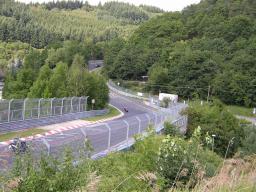 Motorradfahrer auf einer kurvigen Rennstrecke umgeben von grünem Wald