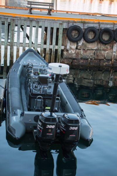 Schlauchboot mit zwei Außenbordmotoren und technischer Ausrüstung im Hafen neben einem Steg mit Reifen als Fender