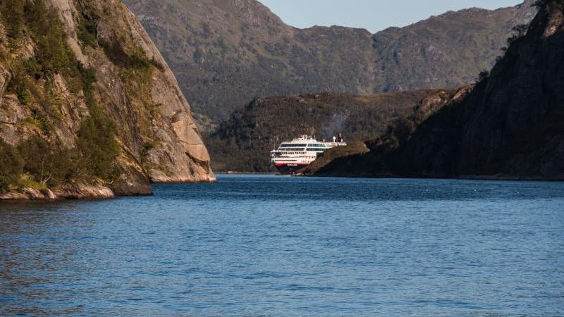 Fjordlandschaft mit Bergen und einem Kreuzfahrtschiff auf dem Wasser