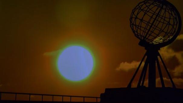 Silhouette einer Metallkugel auf einem Podest vor einem großen Sonnenuntergang