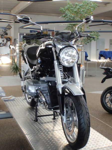 Schwarzes Motorrad steht auf Podest in hellem Ausstellungsraum