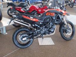 Schwarzes und orangefarbenes Motorrad GS im Ausstellungsraum mit weiteren Motorrädern im Hintergrund