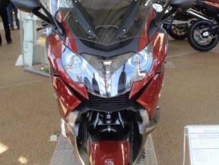 Frontansicht eines roten Motorrads auf einem Messestand mit anderen Motorrädern im Hintergrund