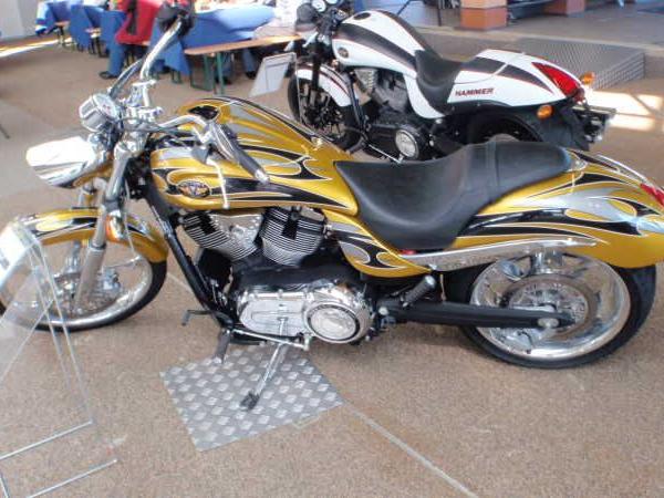 Gelb-schwarzes Motorrad mit Flammenmuster steht in einer Ausstellungshalle neben einem weißen Motorrad