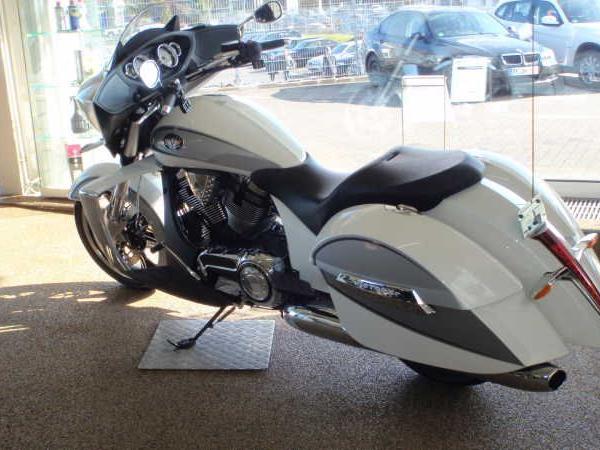 Weiße Cruiser-Motorrad mit seitlichen Verkleidungen in einem Verkaufsraum vor großen Fenstern.