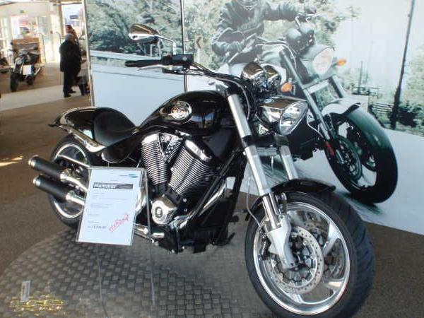 Schwarzes Motorrad präsentiert auf einer Messe vor einer großen Fotowand mit einem Motorradfahrer
