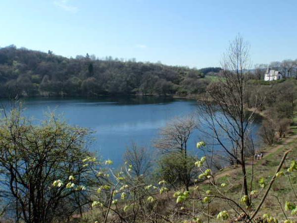 See mit Wald und einem weißen Haus am Ufer unter klarem Himmel