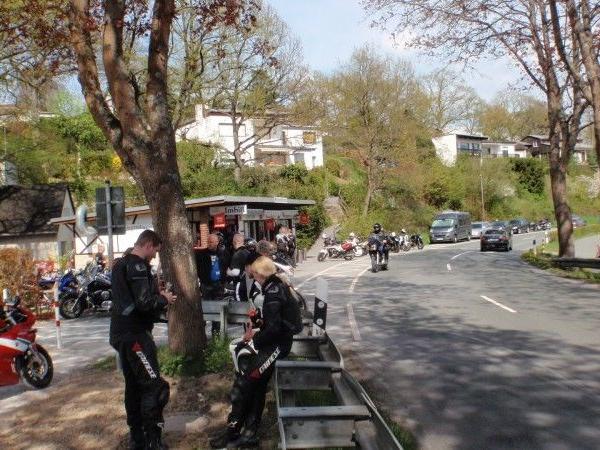 Motorradfahrer in schwarzer Schutzkleidung an einem Rastplatz an einer Landstraße