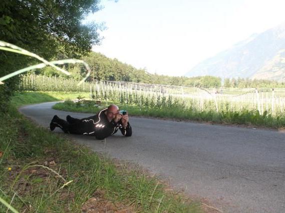 Person liegt auf der Straße und fotografiert die Landschaft