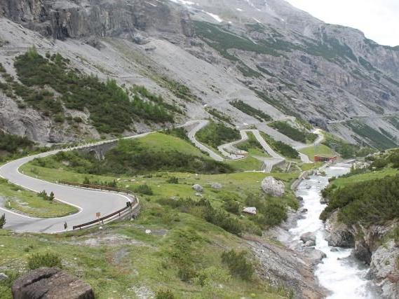 Serpentinenstraße entlang eines Berges mit Fluss und steilen Felswänden