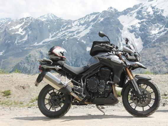 Schwarzes Motorrad vor einer Berglandschaft mit schneebedeckten Gipfeln
