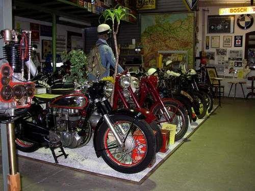 Eine Reihe von historischen Motorrädern in einem Museum mit Dekorationen und Schildern an den Wänden