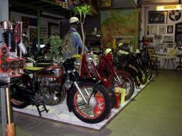 Eine Reihe von historischen Motorrädern in einem Museum mit Dekorationen und Schildern an den Wänden