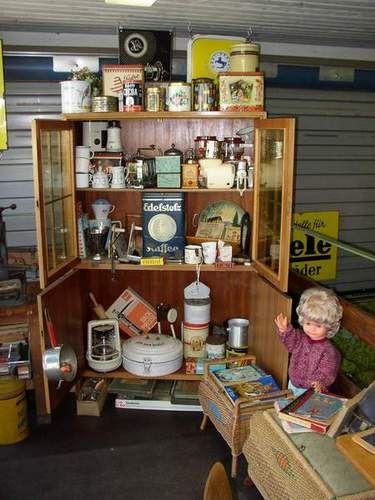 Vitrine mit altertümlichen Haushaltsgegenständen und eine Puppe in einem Raum mit Metallwänden