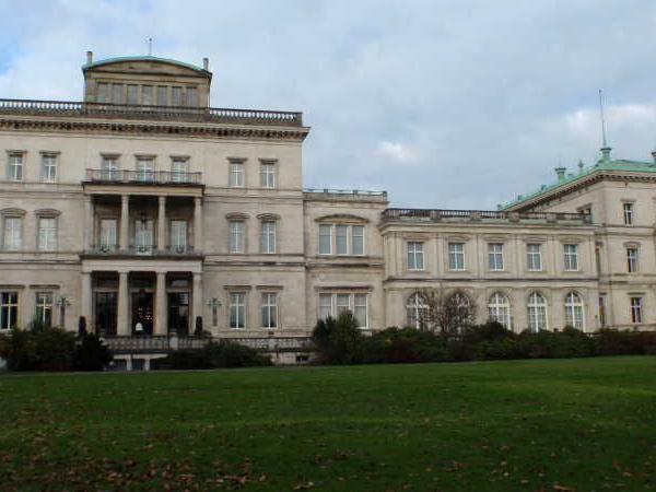 Großes historisches Gebäude mit Säulen und grüner Wiese im Vordergrund