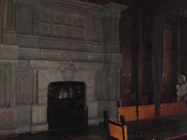 Großer Raum mit historischem Kamin und langem Holztisch mit Stühlen