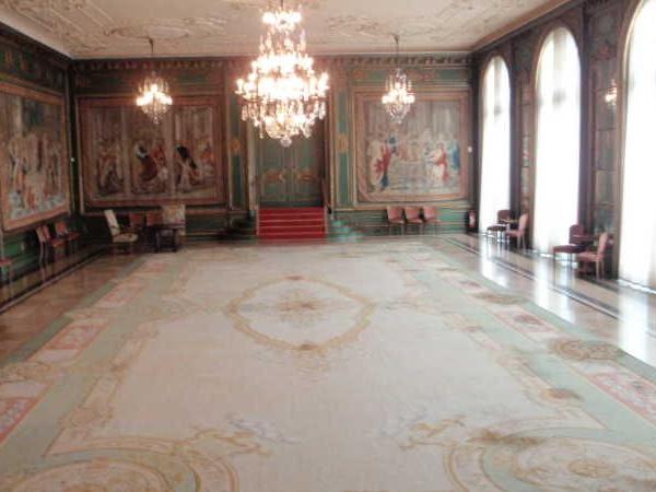 Großer prunkvoller Saal mit Gemälden, Kronleuchtern und Teppichboden