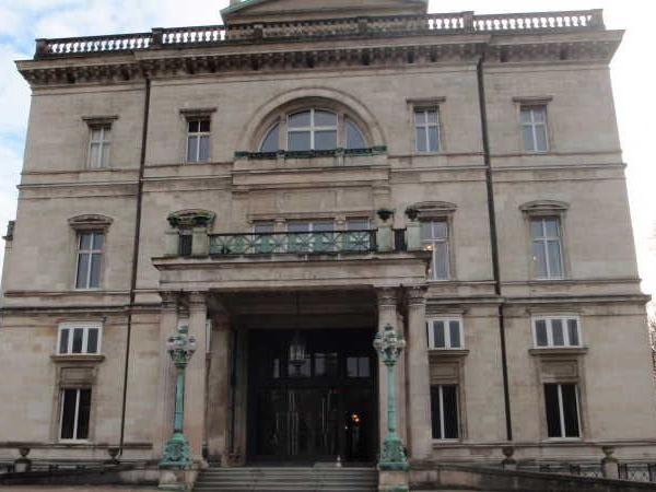 Fassade eines historischen Gebäudes mit großem Eingang und Laternen